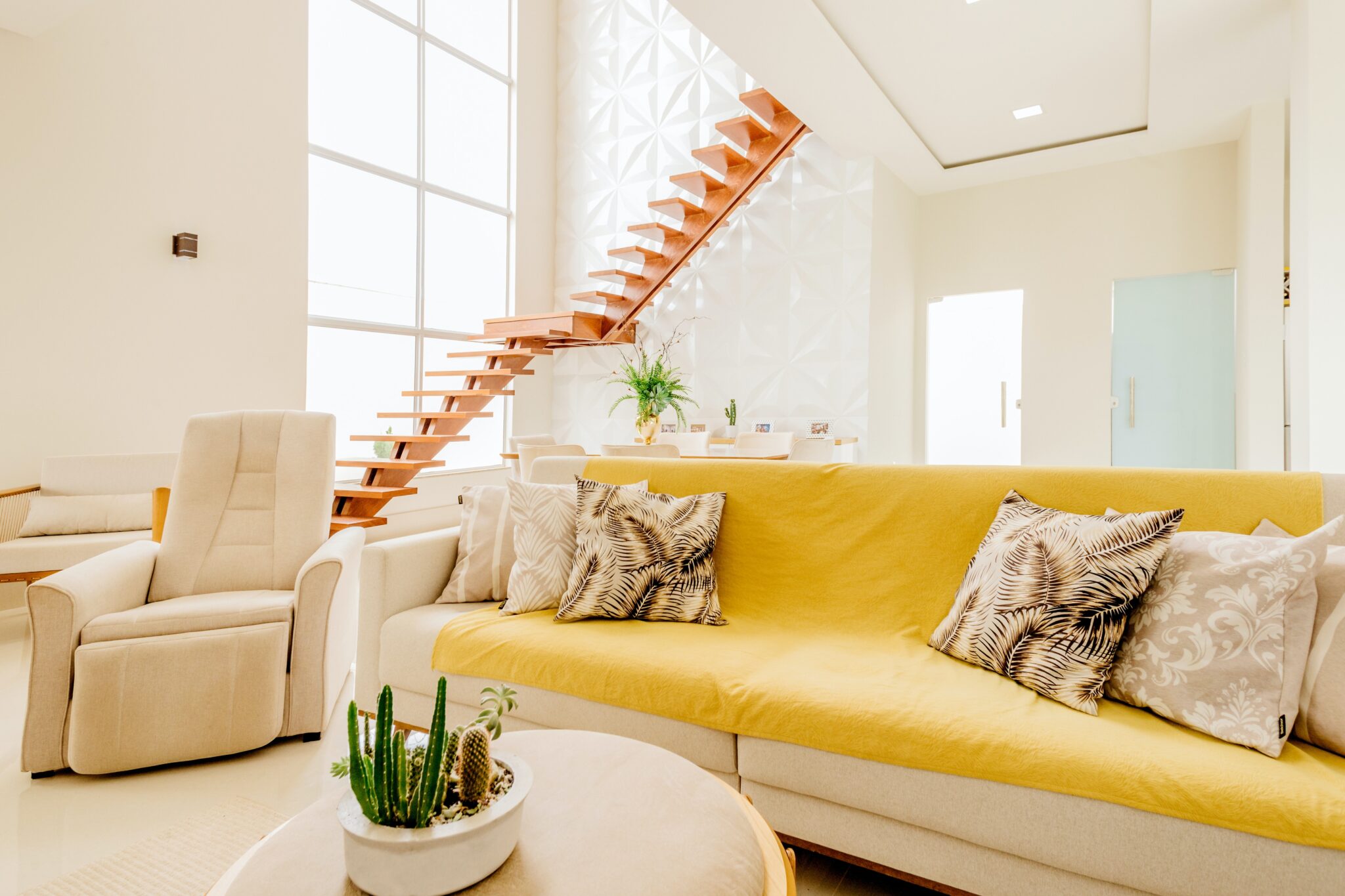 A living room with yellow furniture and stairs.