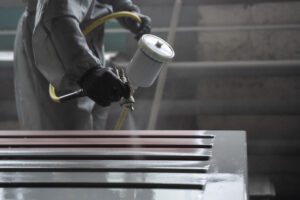 A person spraying paint on some metal.