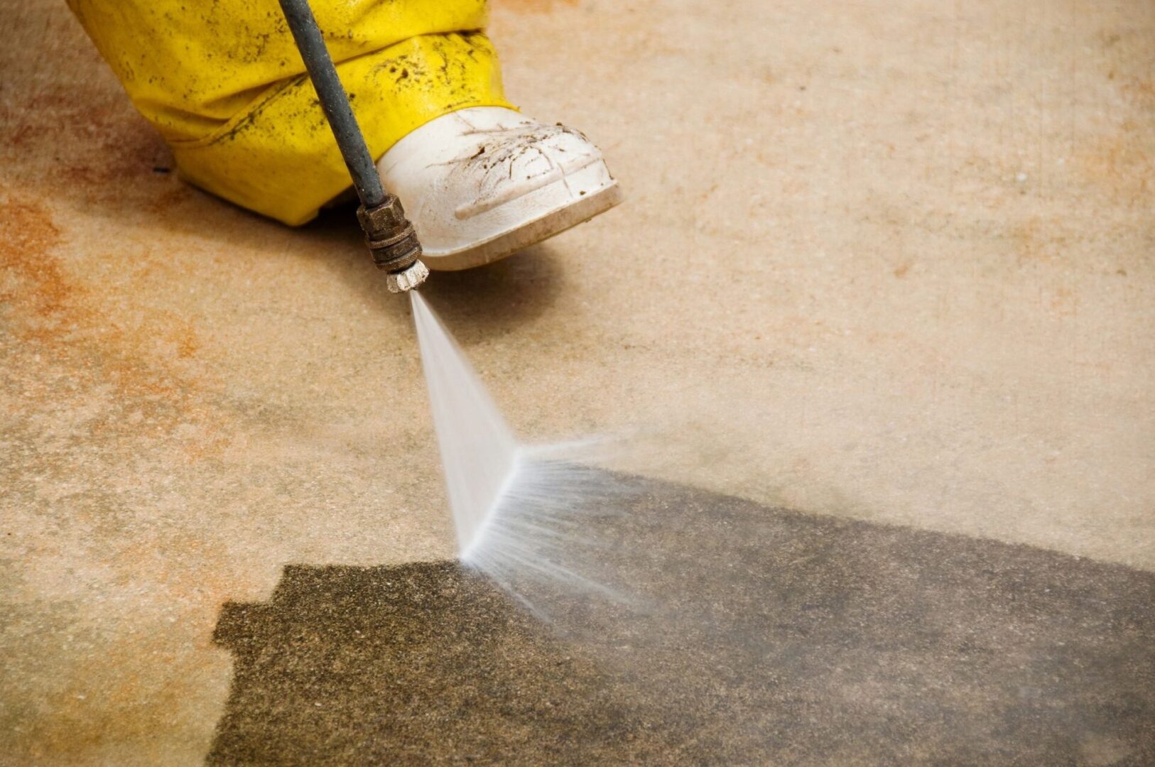 A person using a spray gun to clean the floor.